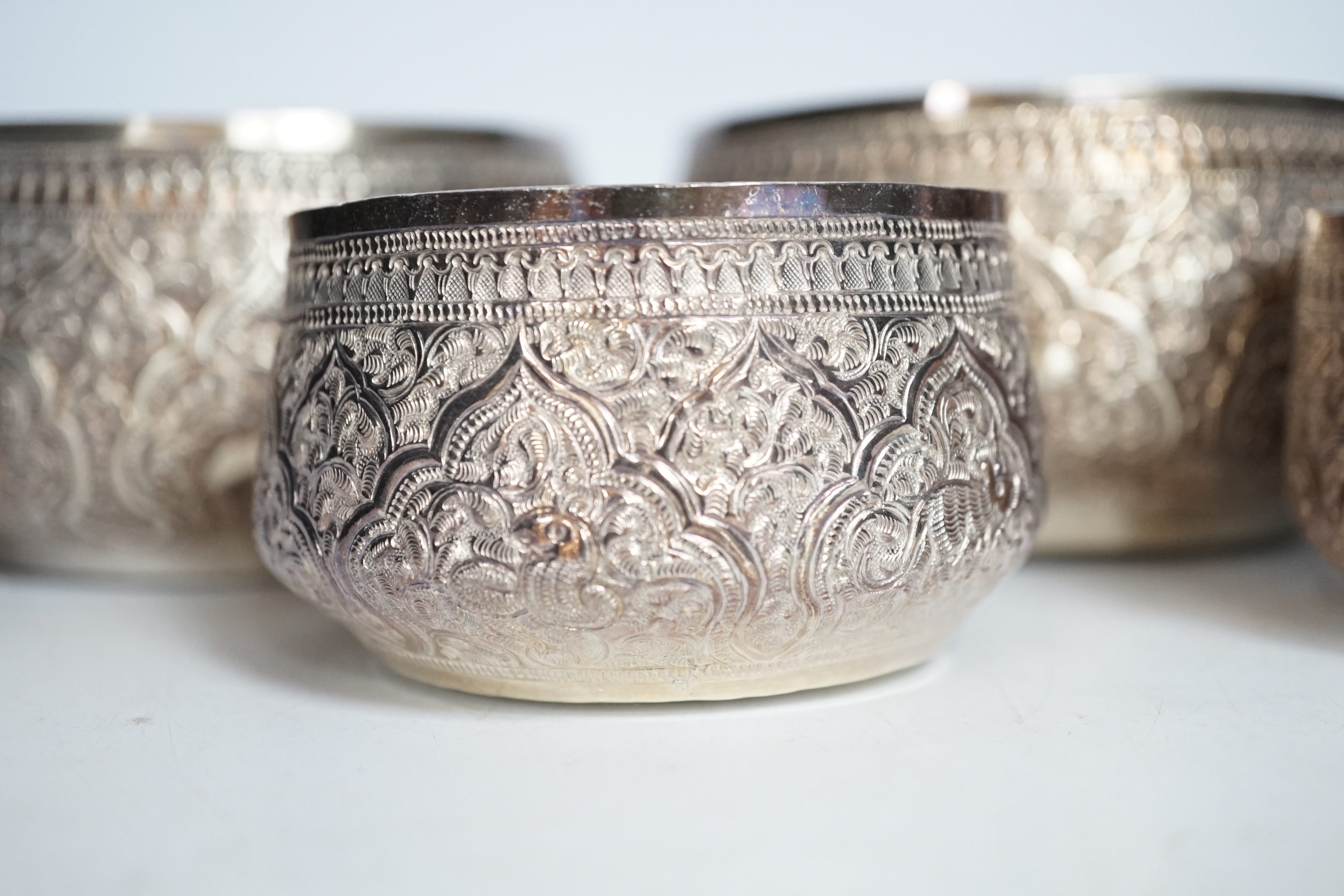 A pair of Thai circular white metal bowls, and a pair of small bowls, all decorated with animals and foliate scrolls, inscribed on bases, diameter 12cm and 8.5cm